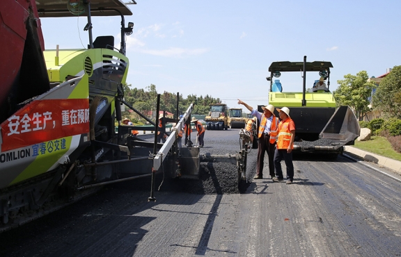 攤鋪機、壓路機等設(shè)備緊張有序運行，高達(dá)170℃的瀝青混合料炙烤著公路人